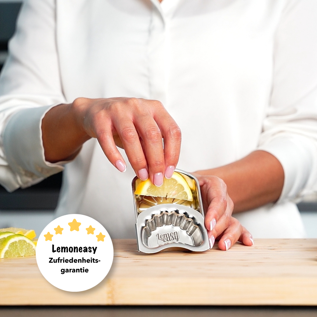 Person legt ein Zitronenstück in den Lemoneasy Zitronenschieber aus Edelstahl ein. Einfache Anwendung mit Zufriedenheitsgarantie für mehr Saft und weniger Kraftaufwand.